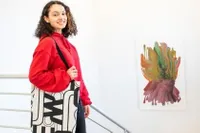 A graphic design student posing in front of a colorful, abstract piece of artwork 