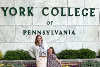 Cassie Childers-Harmer with her daugher in front of a YCP sign. 