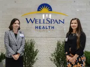 Rachel Rambler and Erica Rinehart pose in front of a WellSpan Health sign. 
