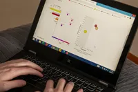 Hands rest on a laptop keyboard. The screen shows charts and graphs analyzing data. 