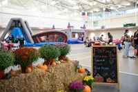 Inflatable slides and a bounce house are in the Grumbacher gym alongside hay bales and mums during Fall Fest 2022. 