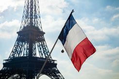 Stock photo of French flag on display in front of the Eiffel Tower.