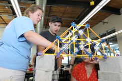 Students in a civil engineering classroom work together to build a model bridge out of plastic pieces