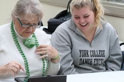 A student works with a resident in a nursing home to use an Ipad.