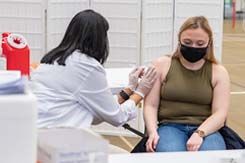 A nurse gives a student a COVID vaccine in the arm during an on-campus clinic.