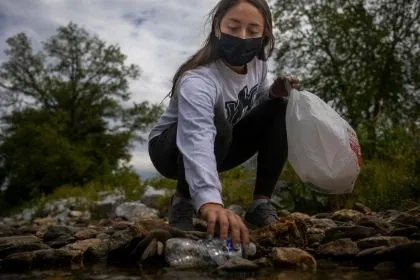 A YCP student cleaning up the trash and plastics in the on-campus creek 
