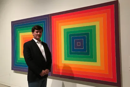 Chris Staub in front of paintings 