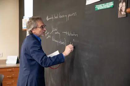 Dominic DelliCarpini writing on a chalk board 