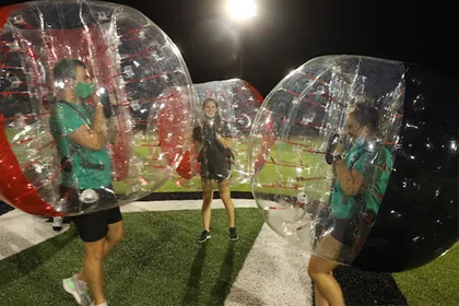 Students face off on the knocker soccer field, all wearing knockerball bubbles over their heads and upper bodies. 