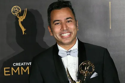 Editor-Director Kabir Akhtar wears a tux and holds an Emmy on the Emmy red carpet. 