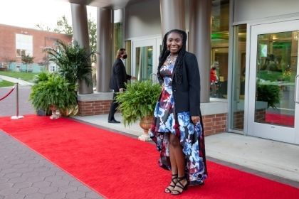 A student posing in front of the WPAC on a red carpet