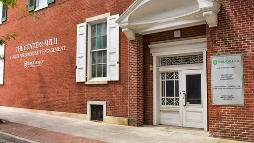 A colonial-style brick building shopfront has a embedded signage reading Gunter-Smith Center for Community Engagement, followed by the York College of Pennsylvania logo.