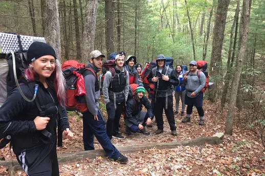 Students pose for a photo on a trail in the woods during backpacking course.