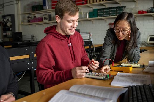 Professor Eleanor Leung works on a circuit sample with a student in an engineering classroom.