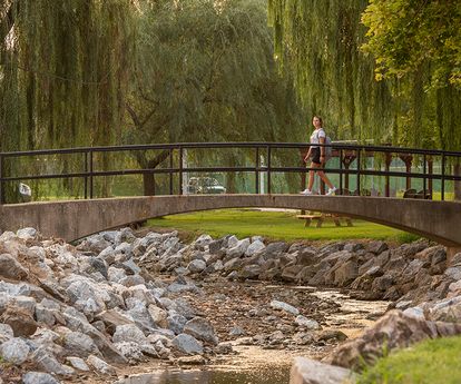 A female student walks across the foot bridge over Tyler Run brook