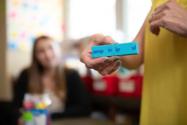 A teacher holds a learning tool that matches letters and helps students learn to read.