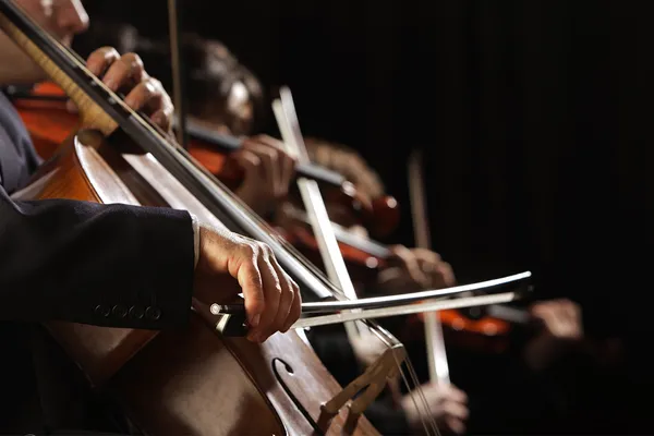 A close-up image shows musicians playing cellos and other string instruments.