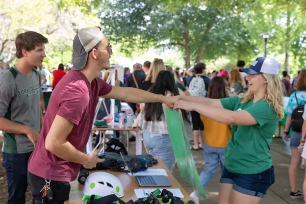 Student volunteers hand out swag at a club table during the fall involvement fair.