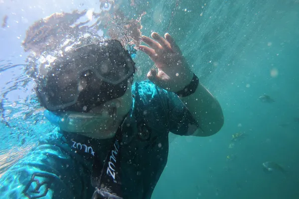Student Isabel Cox waves at a camera underwater while snorkeling in Costa Rica.