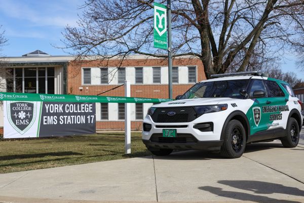 A white van labeled York College EMS is parked in front of a ceremonial ribbon and a sign reading York College EMS Station 17
