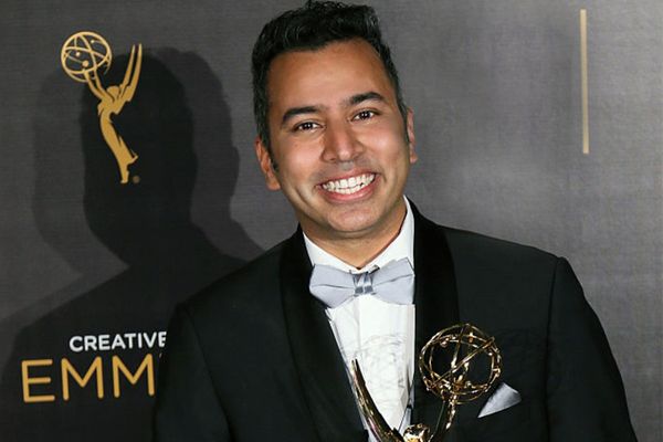 Editor-Director Kabir Akhtar wears a tux and holds an Emmy on the Emmy red carpet.